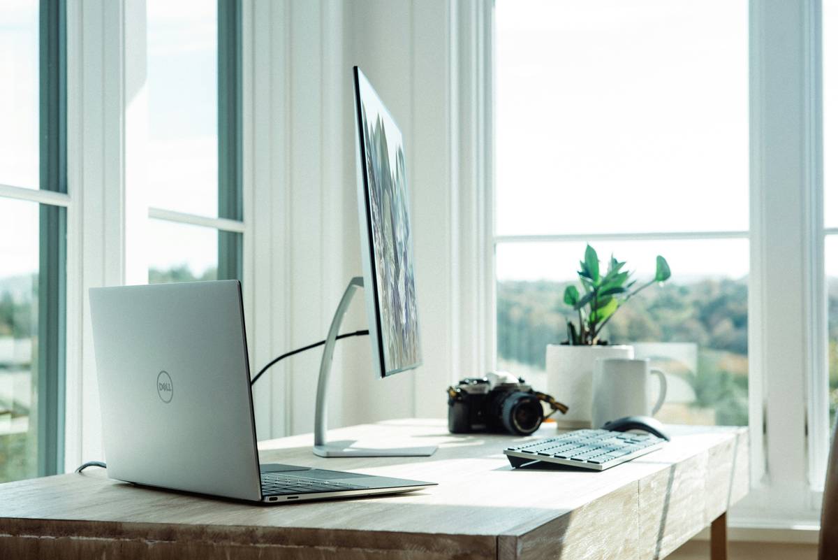 Person speaking to voice activated desk in home office setting while monitors adjust height automatically